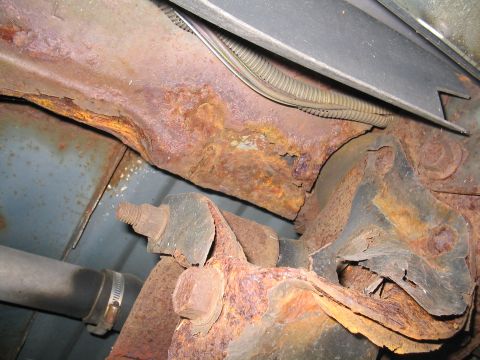 1979 Ford Bronco - Close-up view of severely rusted vehicle frame components and undercarriage parts.