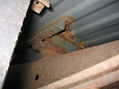 1979 Ford Bronco - Close-up view of the heavily rusted frame and suspension components of an older vehicle.