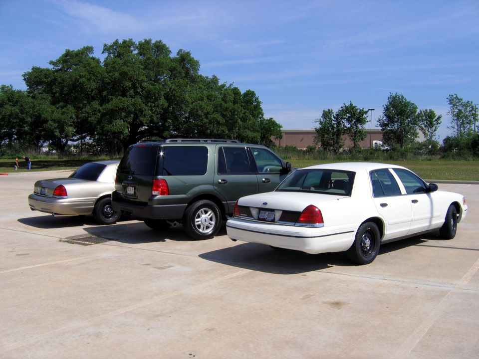 White sedan, green SUV, and tan sedan parked in a lot