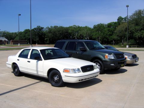 2000 Ford Crown Victoria - A white 2000 Ford Crown Victoria is parked in a lot alongside other vehicles.