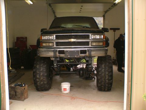 1995 Ford F-150 - Lifted pickup truck with large tires parked inside a garage. Chevrolet emblem visible on the grille.