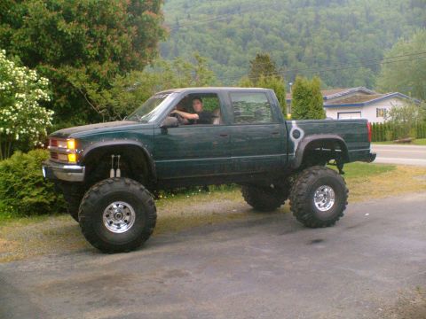 1995 Ford F-150 - This lifted pickup truck has a crew cab and is modified with oversized tires and suspension.
