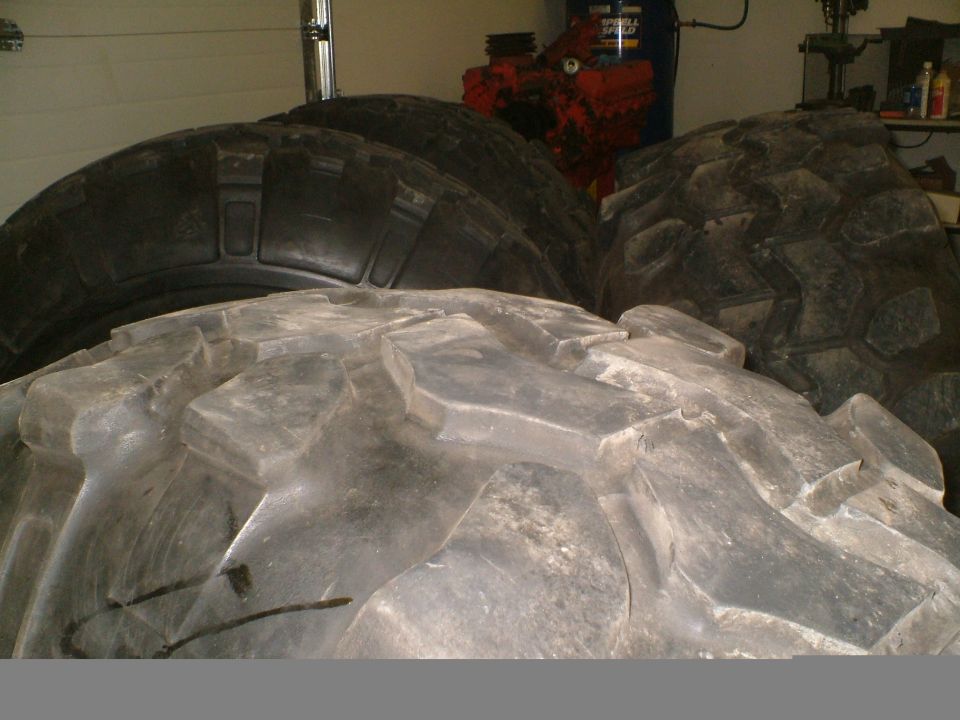 Large off-road tires stacked in a garage