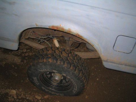 1991 Ford Bronco - The photo shows the rear wheel well of a vehicle, with visible rust and a large off-road tire.