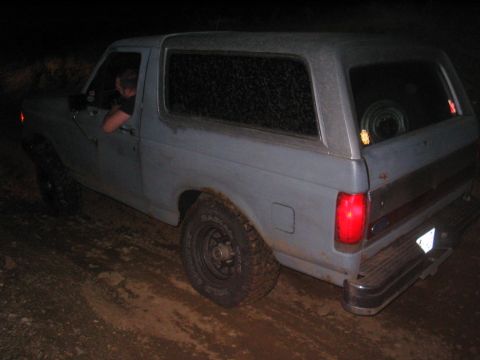 1991 Ford Bronco - Ford Bronco parked on a dirt road at night, with a person visible inside.
