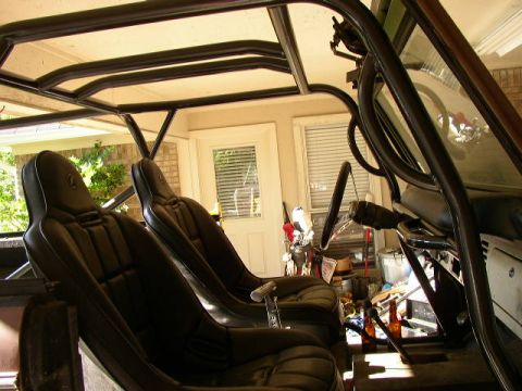 1995 Ford Bronco - The interior of a vehicle shows racing seats and a prominent roll cage, with bottles visible on the floor.
