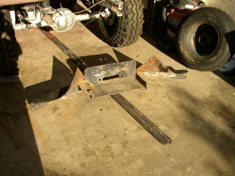 1995 Ford Bronco - Various rusty metal components and a vehicle's rear axle and suspension are visible on a concrete surface.