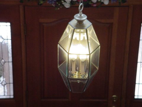 1998 Ford Crown Victoria - A hanging lantern with glass panels and three illuminated bulbs is shown against a dark wooden door.