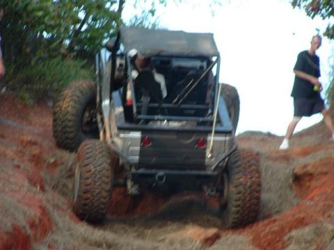 1978 Ford Bronco - A modified off-road vehicle navigates a steep, muddy incline with a person watching.