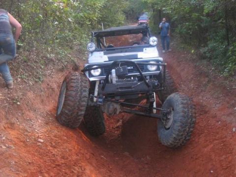 1978 Ford Bronco - An off-road vehicle navigates a steep, muddy trail with another vehicle visible in the background.