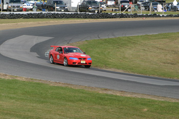 2000 Ford Mustang - Red 2000 Ford Mustang navigates a turn on a paved racetrack.