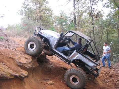 1978 Ford Bronco - Off-road vehicle navigating a challenging dirt trail with a driver and spotter.