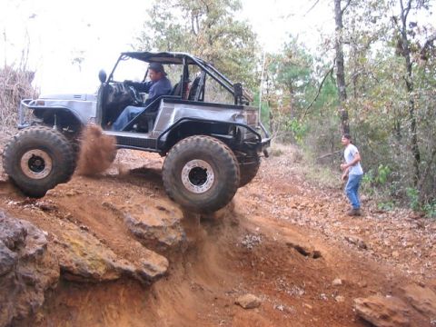 1978 Ford Bronco - A modified off-road vehicle navigates a steep, rocky incline on a dirt trail.