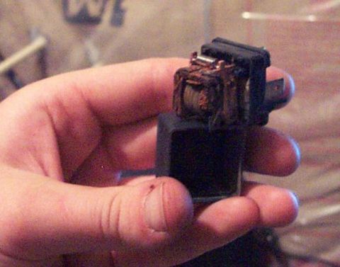 1985 Ford LTD Crown Victoria - A hand holds a worn automotive relay, showing signs of age and corrosion on its internal components.