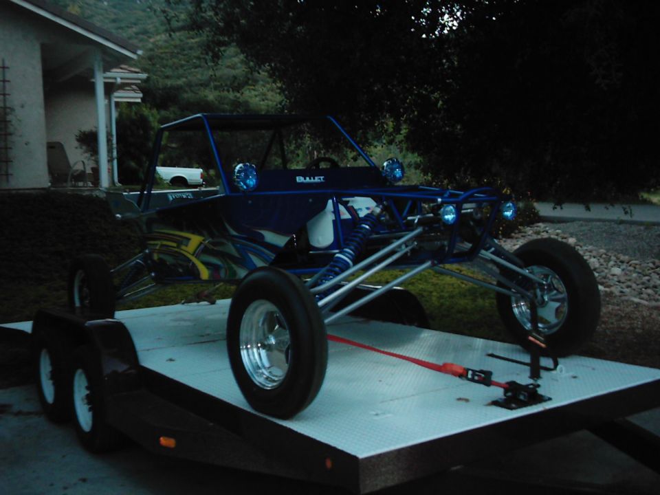 Blue dune buggy with custom graphics on a flatbed trailer