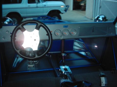 1978 Ford Bronco - The interior of a custom dune buggy is shown, with a light blue 1978 Ford Bronco visible in the background.