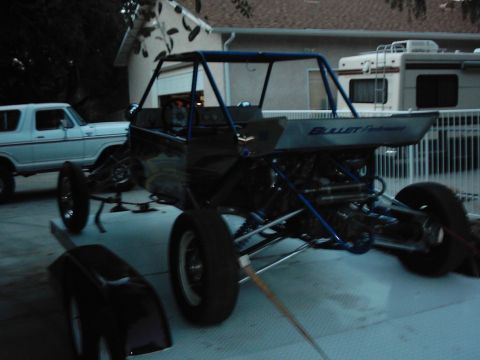 1978 Ford Bronco - A custom dune buggy with a prominent roll cage and exposed engine is parked outdoors next to a white SUV.