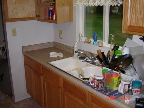 1993 Ford Bronco - A messy kitchen sink area with various items on the counter and a window view of the outdoors.