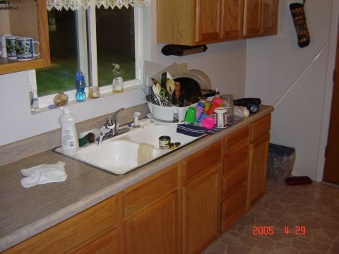 1993 Ford Bronco - A cluttered kitchen sink area with dishes drying and cabinets above and below.