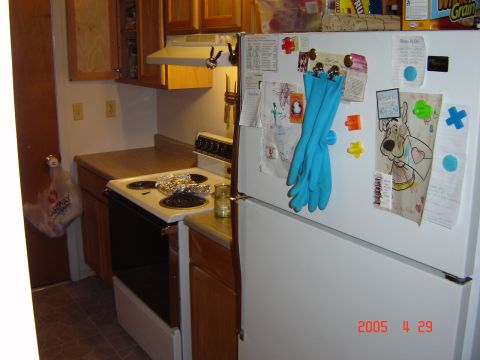 1993 Ford Bronco - A kitchen scene a refrigerator adorned with various items and a stove with foil on its burners.