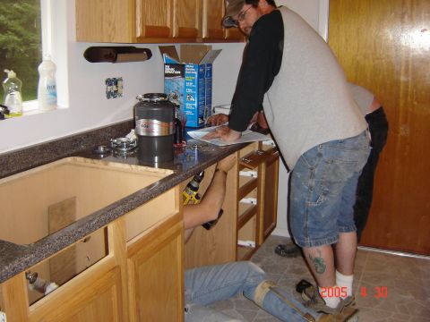 1993 Ford Bronco - Two people work on installing a kitchen countertop and cabinets, with a garbage disposal and sink area visible.