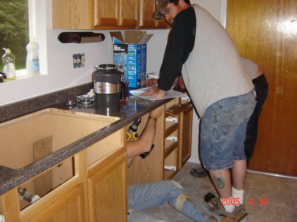 Kitchen renovation with people working on cabinets and countertop