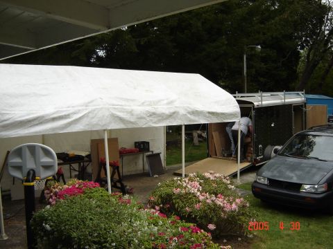 1993 Ford Bronco - A dark sedan is parked next to a trailer and a white tent.