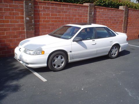 1993 Ford Taurus - This 1993 Ford Taurus sedan is seen from the side, parked in a lot next to a brick wall.
