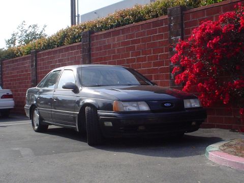 1993 Ford Taurus - This 1993 Ford Taurus is parked in front of a brick wall with red flowers.
