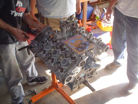 1993 Ford Taurus - Engine block assembly with gasket set, being worked on by mechanics in a garage setting.