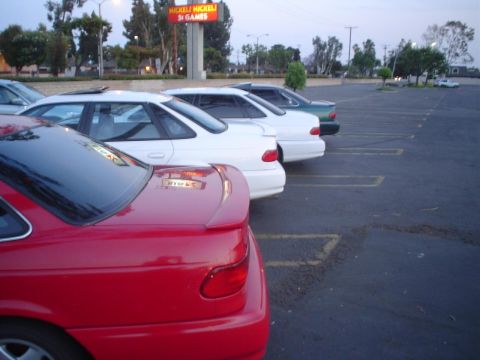 1993 Ford Taurus - A red 1993 Ford Taurus sedan is parked in a lot, with other vehicles visible behind it.