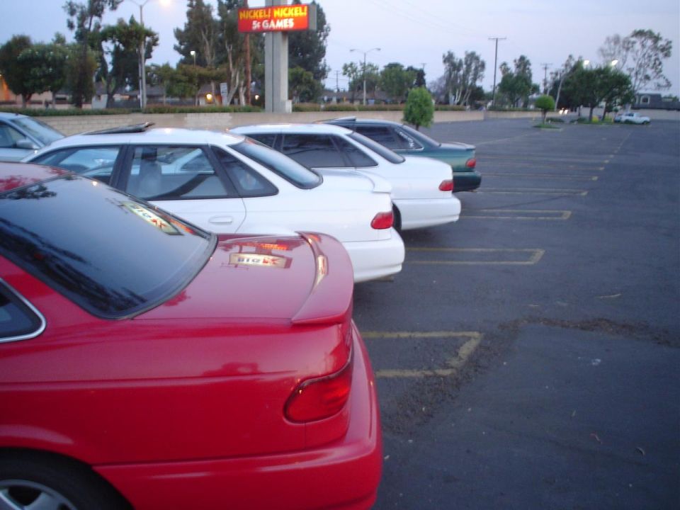 Red 1993 Ford Taurus sedan with a rear spoiler parked in a lot