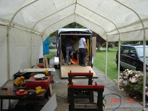 1993 Ford Bronco - A black SUV is parked beside a trailer where two individuals are actively loading equipment.