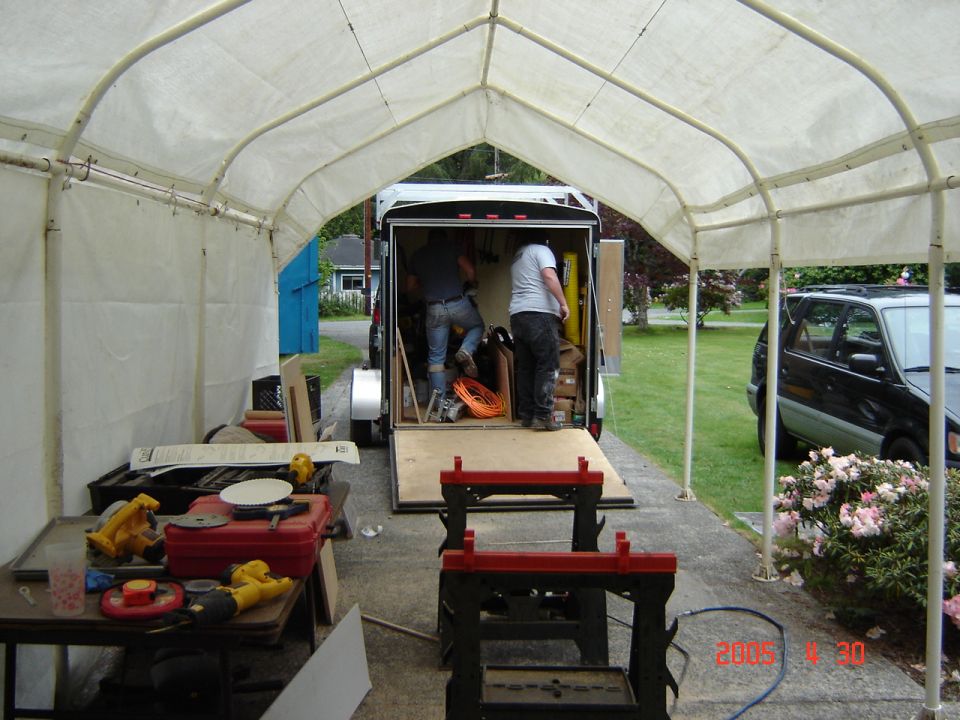 Black SUV parked next to a trailer with people loading items