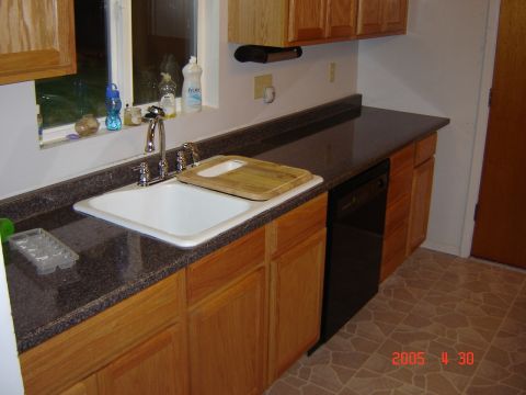 1993 Ford Bronco - A kitchen scene a sink, faucet, cutting board, dishwasher, and wooden cabinets with a window above the sink.