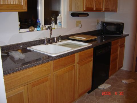 1993 Ford Bronco - A kitchen scene with a double basin sink, wooden cabinets, and a black dishwasher.