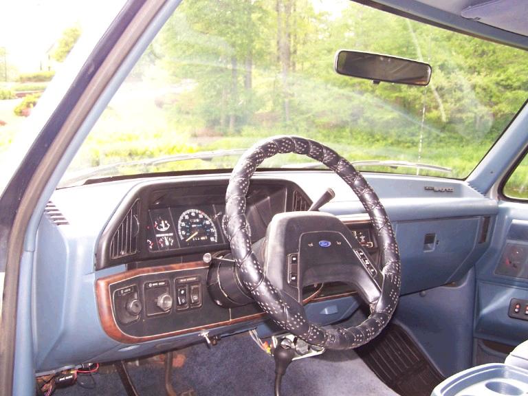 1988 Ford Bronco interior dashboard with aftermarket steering wheel cover and clear gauges