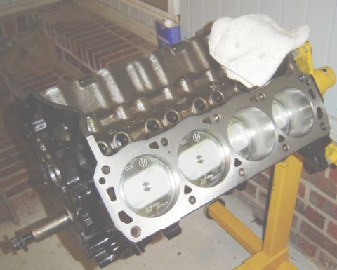 1986 Ford Bronco - Close-up of an engine block with pistons installed, resting on an engine stand.