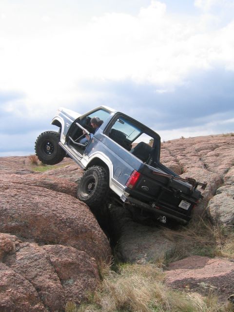 1986 Ford Bronco - An off-road SUV navigates a rocky terrain, demonstrating its climbing capabilities.