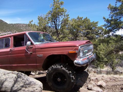 1991 Ford Bronco - This red Jeep Cherokee is shown off-road with a lifted suspension and large tires.