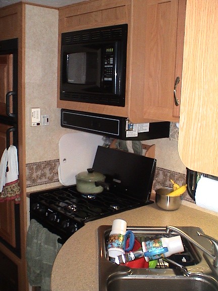 2004 Ford Excursion - The galley with microwave, 3 burner gas stove, oven double sink, dual power fridge (propane/electric)