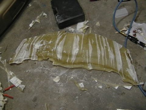 1999 Ford Taurus - A fiberglass part, possibly a body panel, is shown on a concrete floor with tape and debris around it.