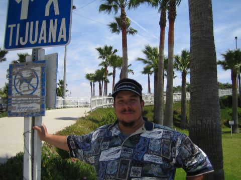 1985 Ford Mustang - Man poses for a photo near a sign indicating Tijuana and a restriction on dogs.
