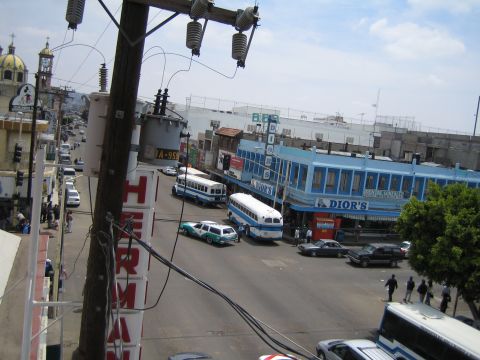 1985 Ford Mustang - A busy street scene with multiple buses and cars, a church steeple visible in the distance.