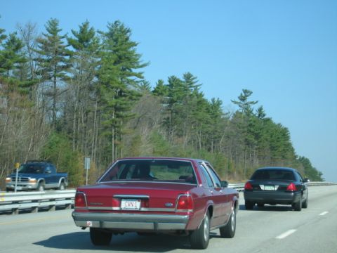 1991 Ford LTD Crown Victoria - Rear view of a red 1991 Ford Crown Victoria LTD on the highway, with another car behind it.