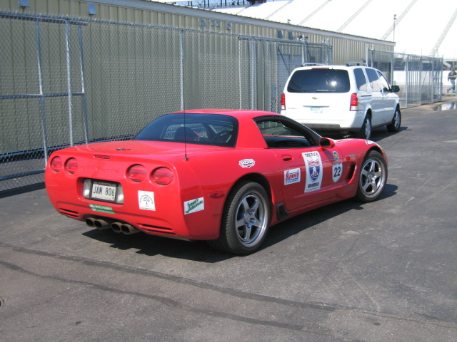 Red sports car with racing decals and license plate JAM 806, rear view