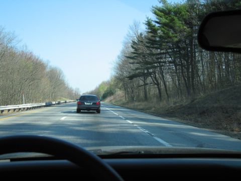 1991 Ford LTD Crown Victoria - A dark sedan travels down a highway, viewed from the perspective of a driver behind it.