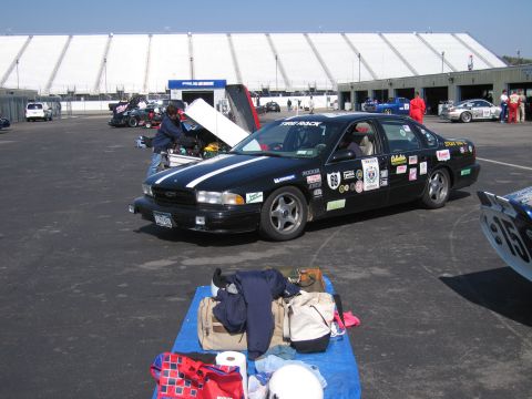 1991 Ford LTD Crown Victoria - A black sedan, likely a 1994 model, is parked at a race track with its hood open and covered in racing decals.
