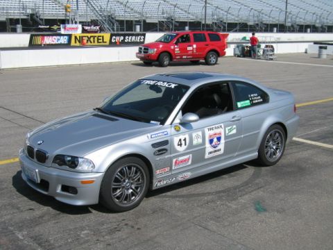 1991 Ford LTD Crown Victoria - Silver BMW M3 coupe on a racetrack, with a red SUV and grandstands visible in the background.