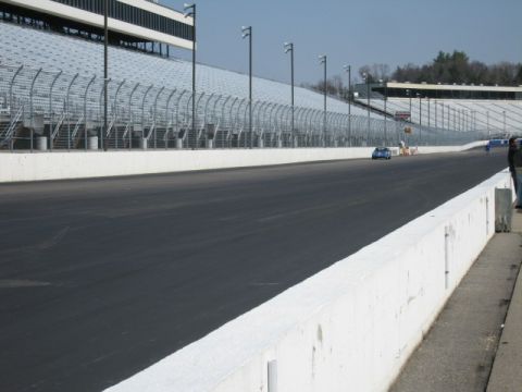1991 Ford LTD Crown Victoria - A blue race car drives on a track in front of empty grandstands.